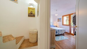 A room with a bed, a wicker basket, and a poster on the wall.