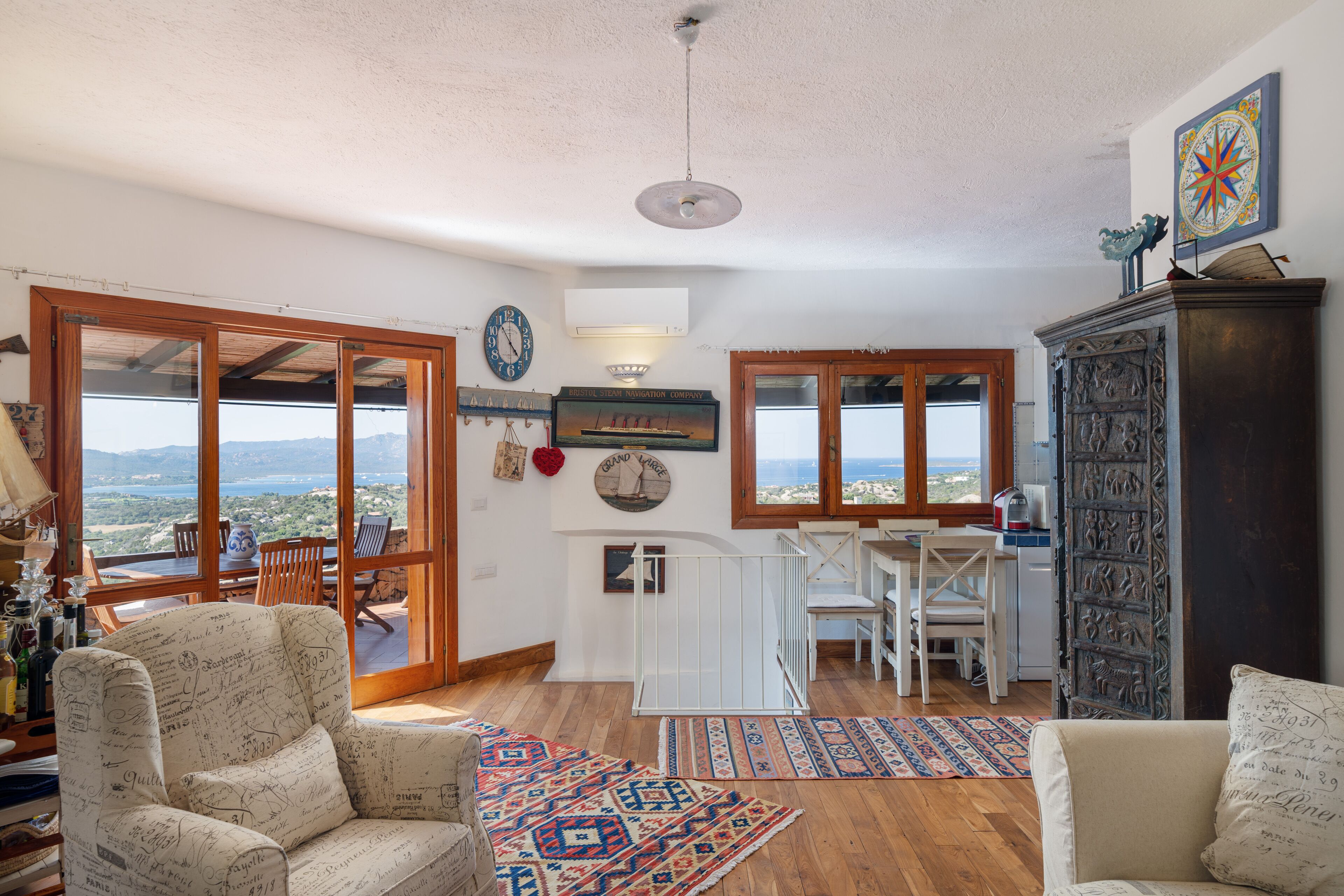 Uma sala de estar ampla com uma grande janela, uma mesa de jantar e um espaço de estar aconchegante.