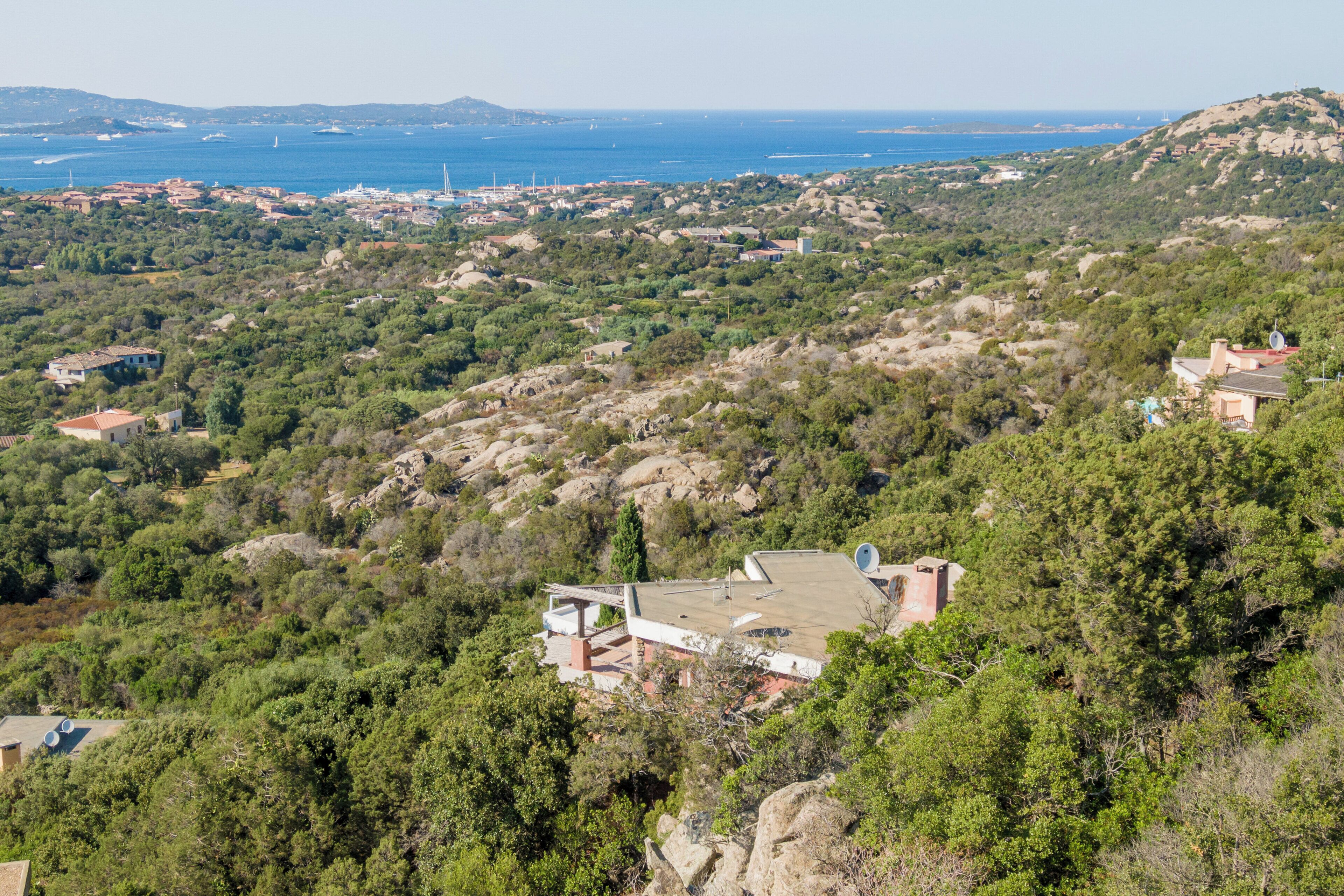 A coastal landscape with a building featuring a flat roof and a satellite dish.