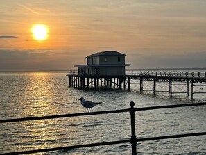 A pier extending into calm waters with a small building at the end.