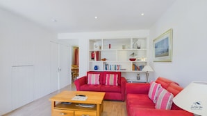 A modern living room with a red sofa, wooden coffee table, and a white bookshelf. - Vermont Your Peaceful West Bay Retreat (Yarmouth)