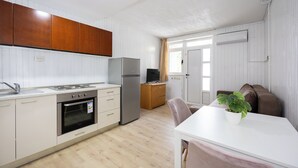 A compact kitchen with white cabinets, a stainless steel refrigerator, and a built-in oven. - Villa Vinovo 1 Bedroom Apartment (Kastela)