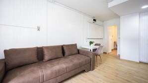 A modern living room with a brown sofa, a white table, and a wooden floor. - Villa Vinovo 1 Bedroom Apartment (Kastela)