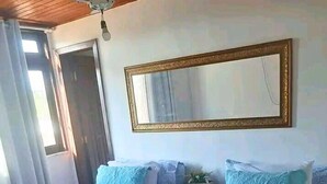 A hotel room with two single beds, a wooden ceiling fan, a large mirror, and a window with curtains. - Pousada da Mércia (Salvador)
