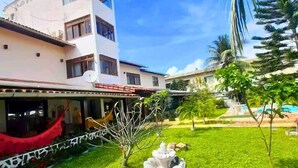 A courtyard with a fountain, a building with balconies, and a palm tree. - Pousada da Mércia (Salvador)