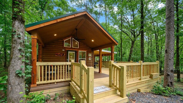 A log cabin with a wooden deck and a welcome mat. - Grin & Bear It: brand new tiny home 1 bdr + loft w/ hot tub (Broken Bow)