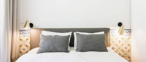 Ein ordentlich bezogenes Bett mit Kopfteil, zwei Kissen und einer Decke.