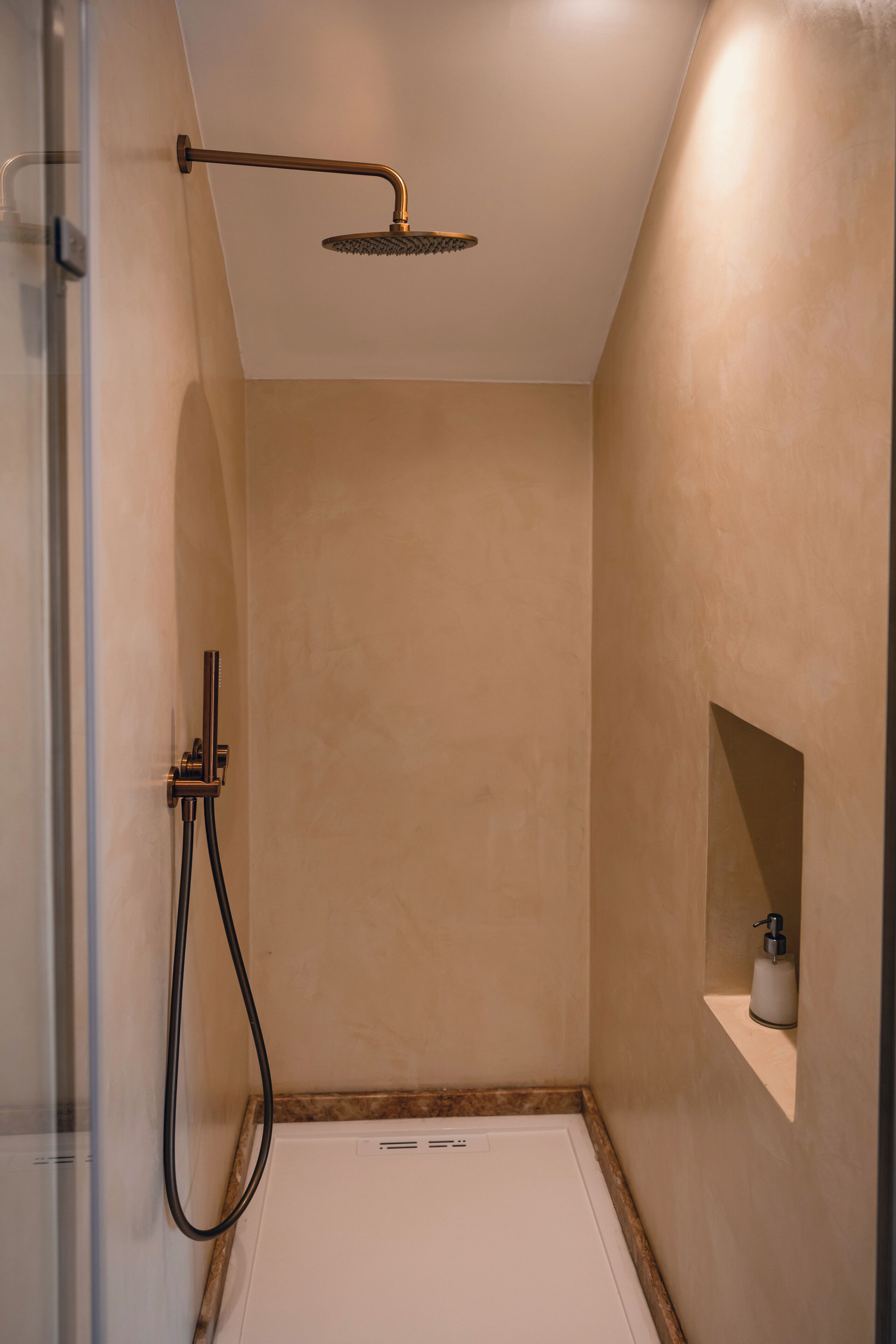 A modern shower with a handheld showerhead and a wall-mounted faucet.
