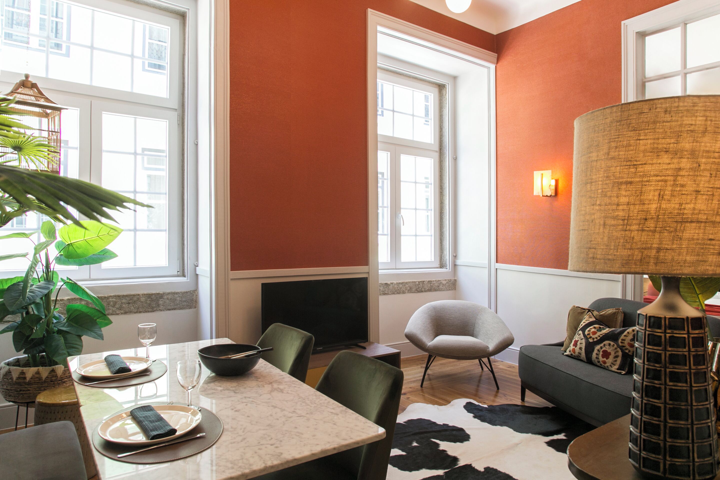 A modern living room with a dining area, large windows, and a fireplace.