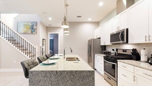 A modern kitchen with granite countertops, stainless steel appliances, and white cabinetry.