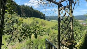 A wooden pergola structure with a view of a green landscape, including hills and a distant village. - Holiday Apartment Cherry Blossom (Schuttertal)