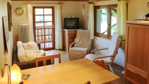 A room with a wooden dining table, two chairs, a television, and a window with curtains. - Holiday Apartment Cherry Blossom (Schuttertal)