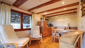 A cozy kitchen with wooden beams, a dining area with chairs, and a view of the outside. - Holiday Apartment Cherry Blossom (Schuttertal)