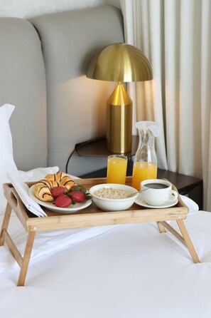 Un plateau de petit-déjeuner avec des croissants, des fraises, des céréales, du café et du jus d’orange, le tout disposé sur un plateau en bois.