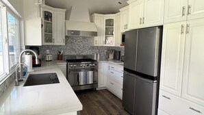 Una cocina moderna con armarios blancos, electrodomésticos de acero inoxidable y un salpicadero de azulejos.