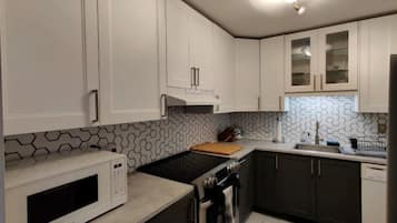 Enjoy cooking in this well-equipped kitchen with a stainless steel range hood, microwave, and black stovetop.