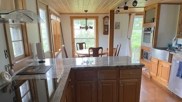 A kitchen with wooden cabinets, a granite countertop, and a dining area with a table and chairs.