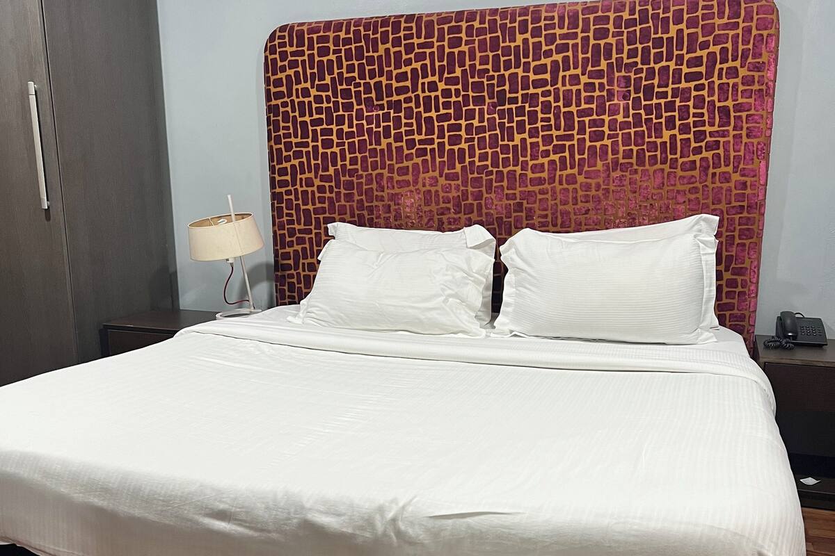 Une chambre d’hôtel avec un grand lit, une armoire, une lampe de chevet et un téléphone sur la table de chevet.
