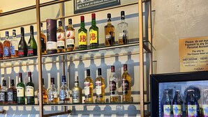 A bar area with shelves of liquor bottles and a refrigerated display of Guinness beer.