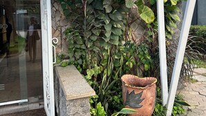 A building entrance with a covered porch, stone wall, and potted plants.
