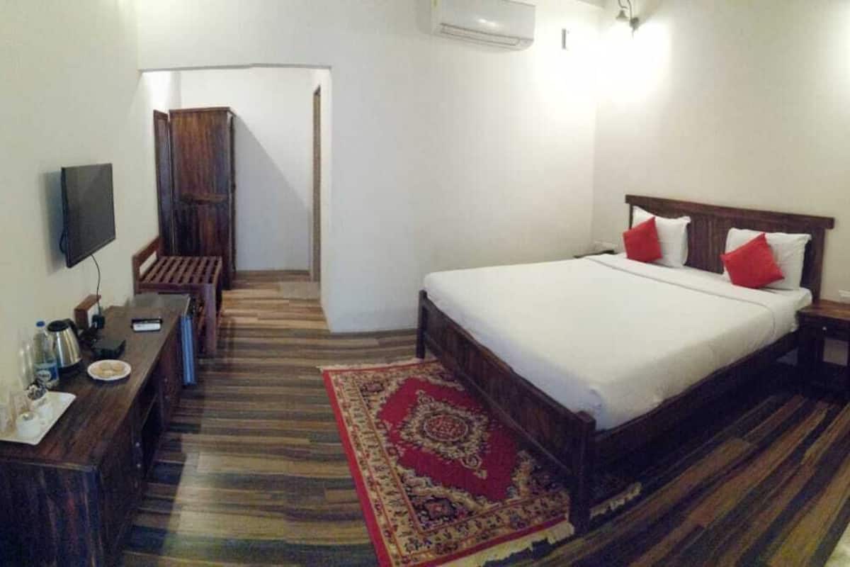 Une chambre d’hôtel avec un lit, un bureau, une chaise, une télévision et une petite table.