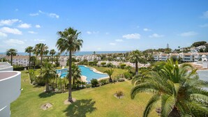 A resort with a swimming pool, palm trees, and a view of the sea. - M11 Antares - Apartment (Sitio de Calahonda)