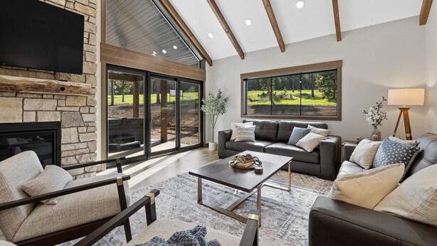 Un salón amplio con chimenea de piedra, ventanas grandes y un diseño moderno de techo.