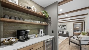 Una cocina moderna con estantes de madera, cafetera y lavavajillas.