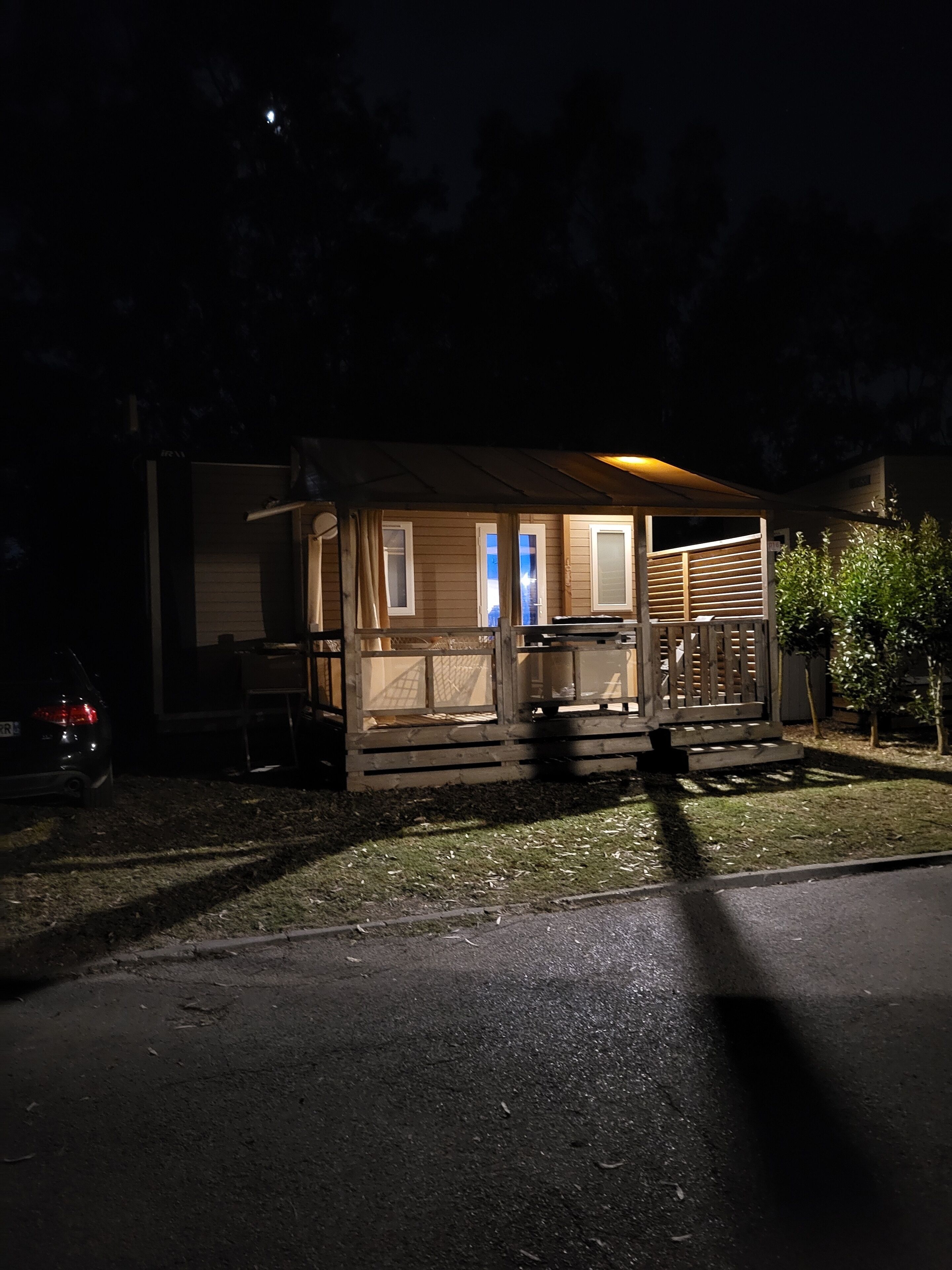 A small, single-story cabin with a porch and a car parked in front.