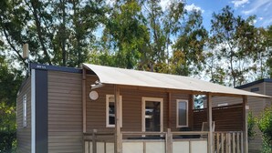 Eine kleine, eingeschossige Holzhütte mit einer Veranda und einem überdachten Bereich im Freien.