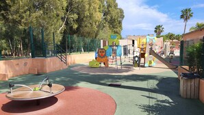 Ein Spielplatz mit einem roten und grünen Spielbereich, einer Rutsche und einer Kletterkonstruktion.