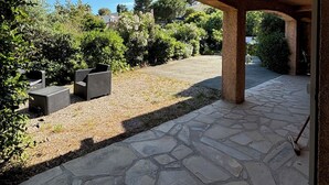 An outdoor patio area with stone flooring and a thatched roof structure. - Appartement 70m2 Climatisé à Saint Aygulf (frejus)