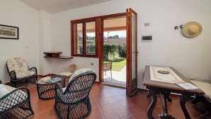 A room with a dining table, two wicker chairs, a small shelf, and a door leading to an outdoor area. - Gian s Home by Wonderful Italy (San Teodoro)
