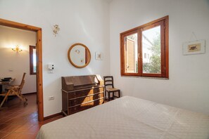 Ein Schlafzimmer mit Bett, Kommode, Stuhl und einem Fenster mit Blick.