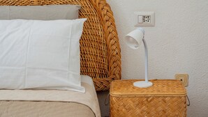 A bed with white bedding, a wicker headboard, a bedside lamp, and a power outlet on the wall. - Gian s Home by Wonderful Italy (San Teodoro)