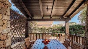 A wooden table with a fruit bowl, surrounded by wooden chairs, under a wooden pergola with a stone wall on one side. - Gian s Home by Wonderful Italy (San Teodoro)