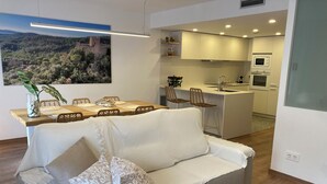 Una sala moderna con un sofá, una mesa de comedor y una cocina al fondo.