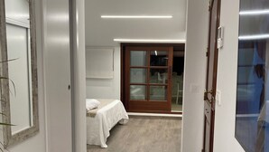 Een gang met een bed, een deur en een spiegel.