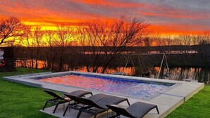 Une piscine avec des chaises longues et une vue sur le coucher du soleil.