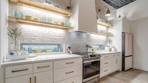 Une cuisine moderne avec des meubles blancs, un four encastré et une hotte de cuisson en acier inoxydable.