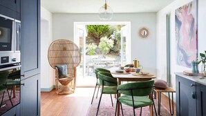 Une cuisine moderne avec un coin repas, comprenant un four Bosch, des chaises en osier et une vue sur le jardin.