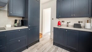 Una cocina moderna con armarios oscuros, una cafetera, un hervidor rojo y un tostador.