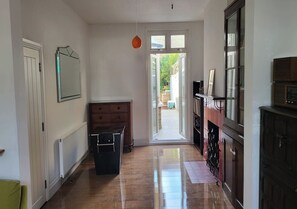 Un couloir avec un radiateur, une armoire en bois et une porte donnant sur un jardin.