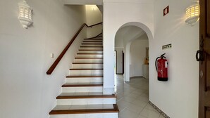Una escalera de madera con paredes blancas que conduce a un arco.