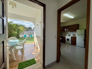 A kitchen with a washing machine, a refrigerator, and wooden cabinets.