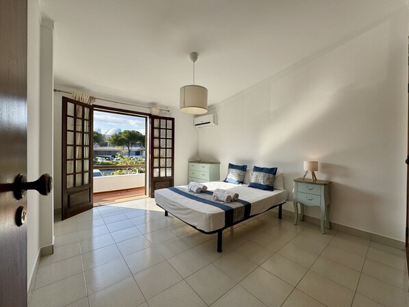 A bedroom with a bed, bedside tables, a lamp, and a view through a sliding door.