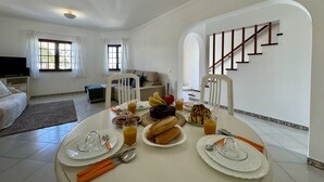 Un comedor con una mesa dispuesta para el desayuno, un sofá y una escalera.