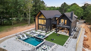 Ein modernes Haus mit Pool, Sitzgelegenheiten im Freien und einer großen Terrassenfläche.