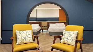 A hotel room with two yellow armchairs, a wooden table, and a bed with white bedding. - Parcel Hotel Bangkok (Bangkok)