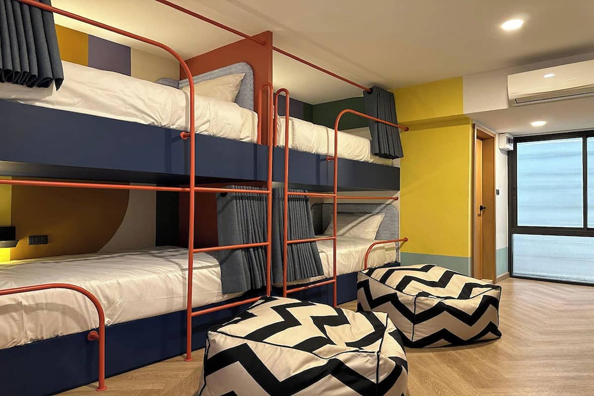 A dormitory room with bunk beds, a window, and a door.